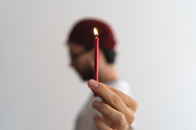 Zbliżenie zapalonej świecy trzymanej przez młodego mężczyznę w czapce zamazane pole Zdjęcie artystyczne