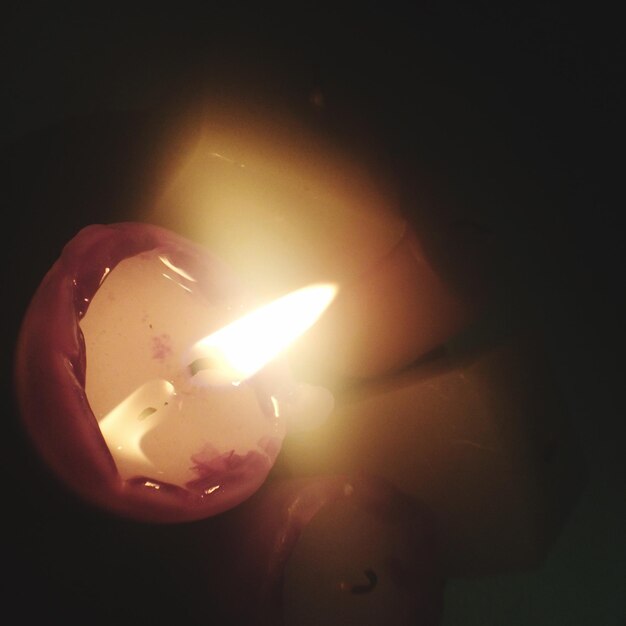 Zdjęcie zbliżenie zapalonej świecy w ciemnym pokoju