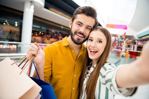 Zbliżenie zdjęcie atrakcyjne śmieszne damy przystojny facet para odwiedzić centrum handlowe razem nosić wiele toreb pakuje, co selfies dobry nastrój nosić strój dorywczo koszula w pomieszczeniu