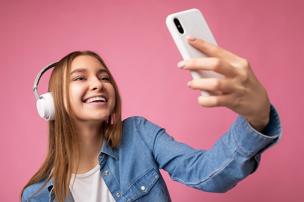 Zbliżenie zdjęcie atrakcyjnej szczęśliwej uśmiechniętej młodej kobiety blondynka w niebieskiej dżinsowej stylowej koszuli and