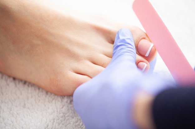 Zbliżenie zdjęcie kobiece stopy w salonie spa na Pedicure Procedur.Care. Piękne kobiece stopy z pedicure w salonie piękności. Manicure Spa