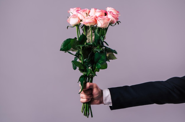 Zbliżenie zdjęcie męskiej ręki trzyma bukiet róż. Koncepcje uroczystości, świąt i prezentów. Dzień Świętego Walentego. Dzień Zakochanych