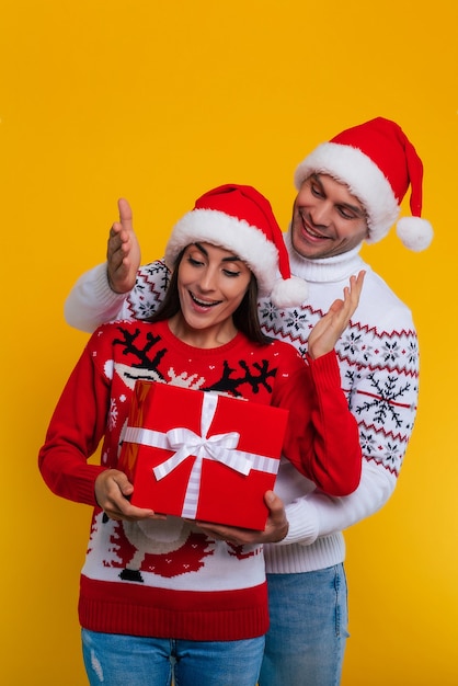 Zbliżenie zdjęcie pięknej szczęśliwej i podekscytowanej młodej pary zakochanej w świątecznych ubraniach z pudełkami w rękach, podczas gdy oni świętują Nowy Rok i dają sobie prezenty