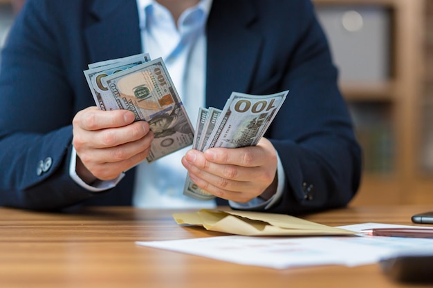 Zbliżenie zdjęcie rąk biznesmena liczącego gotówkę dolary amerykańskie mężczyzna pracujący w biurze