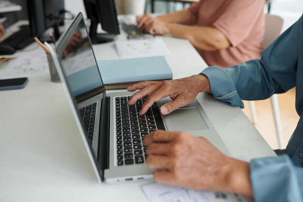 Zbliżenie zdjęcie starszego mężczyzny piszącego na laptopie podczas zajęć komputerowych