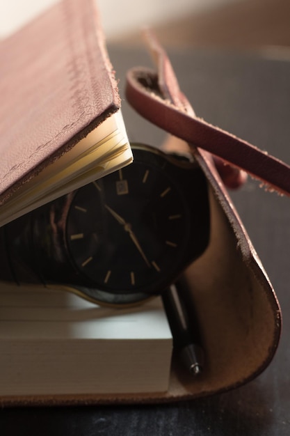 Zdjęcie zbliżenie zegarka z książką na stole