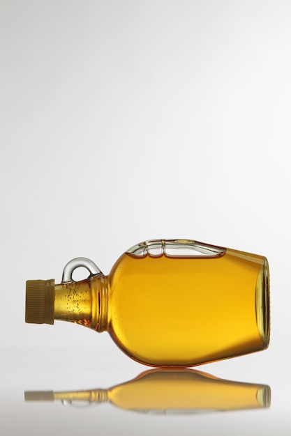 Zdjęcie zbliżenie żółtego syropu w butelce na białym tle