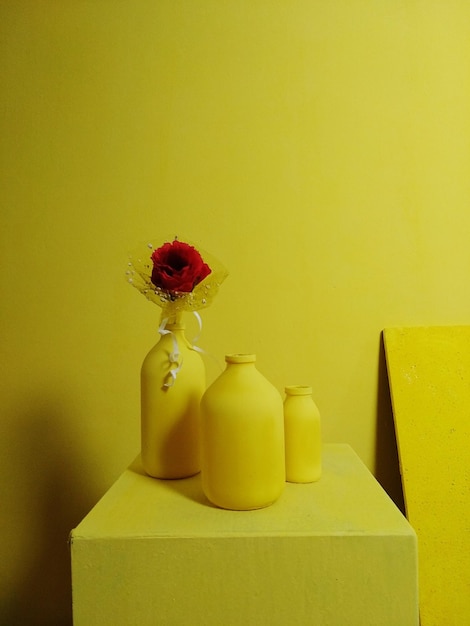 Zdjęcie zbliżenie żółtego wazonu z kwiatami na stole przy ścianie