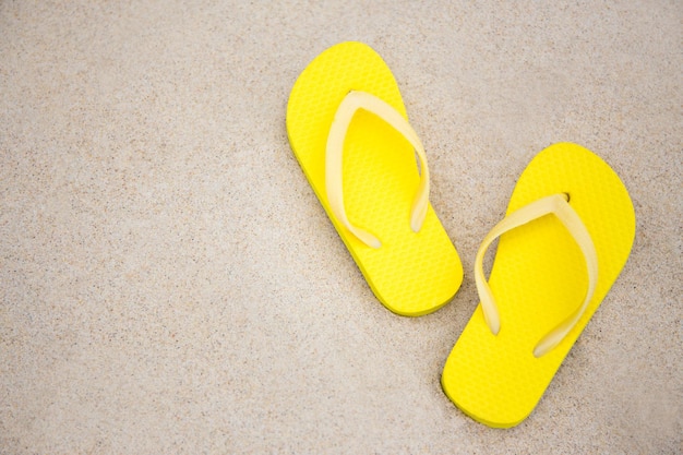 Zdjęcie zbliżenie żółtych klapek i miejsca na kopię na piaszczystej plaży