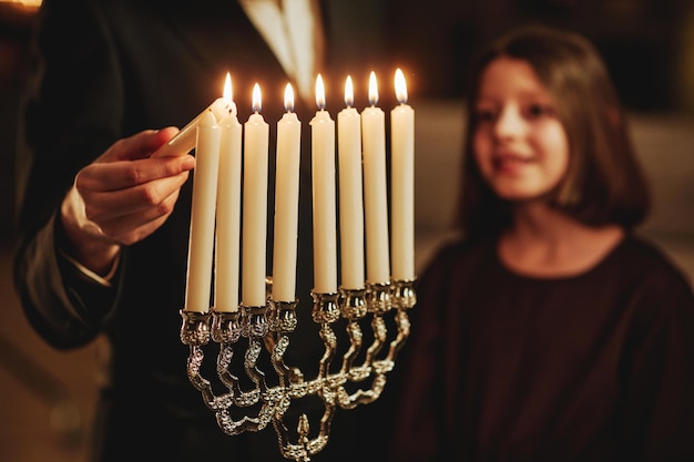 Zbliżenie żydowskiego człowieka zapalającego srebrną świecę menorową podczas chanukowej celebracji miejsca kopiowania