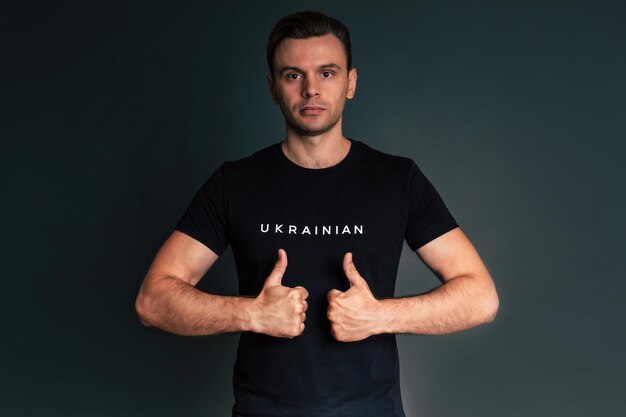 Zbliżone zdjęcie studijne młodego człowieka z Ukrainy w czarnej koszulce z znakiem lub hasłem wojna ukraińska na Ukrainie Pomóż i wspieraj silny naród Walka o sprawiedliwość wolność i demokrację