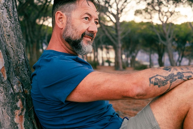 Zbliżony portret dorosłego mężczyzny z brodą, uśmiechającego się i cieszącego się czasem relaksu w parku Szczęśliwi i pogodni ludzie z wesołym wyrazem twarzy Dzień dobry Przystojny mężczyzna 50 lat na zewnątrz Miejsce natury