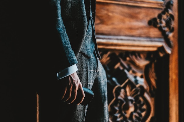 Zdjęcie zbliżony zdjęcie młodego mężczyzny w klasycznym szafkowym garniturze z wygrawerowanymi drzwiami za plecami