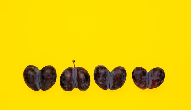 Zdeformowane zrośnięte owoce brzydkie suszone śliwki w jednym rzędzie Podwójne owoce w kształcie serca na żółtym tle