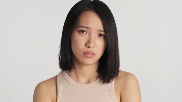 Zdenerwowana Azjatycka kobieta nieszczęśliwa z powodu złych wiadomości na białym tle Kobieta smutna na białym tle Niezadowolona twarz