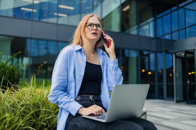 Zdenerwowana kaukazyjska studentka freelancerka kobieta odpoczywa używa laptopa, komputera, rozmawia przez telefon komórkowy