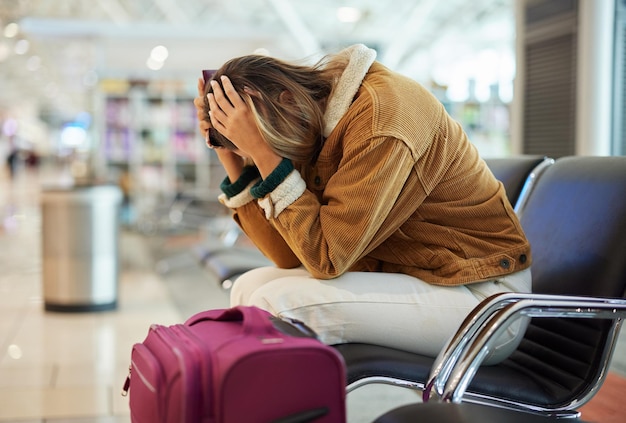 Zdjęcie zdenerwowana kobieta lotnisko i opóźnienie lotu siedząca na ławce w ograniczeniach podróży lub odwołaniu samolotu z bagażem wściekła smutna lub rozczarowana kobieta z frustracji z powodu braku czasu rozkładu wejścia na pokład