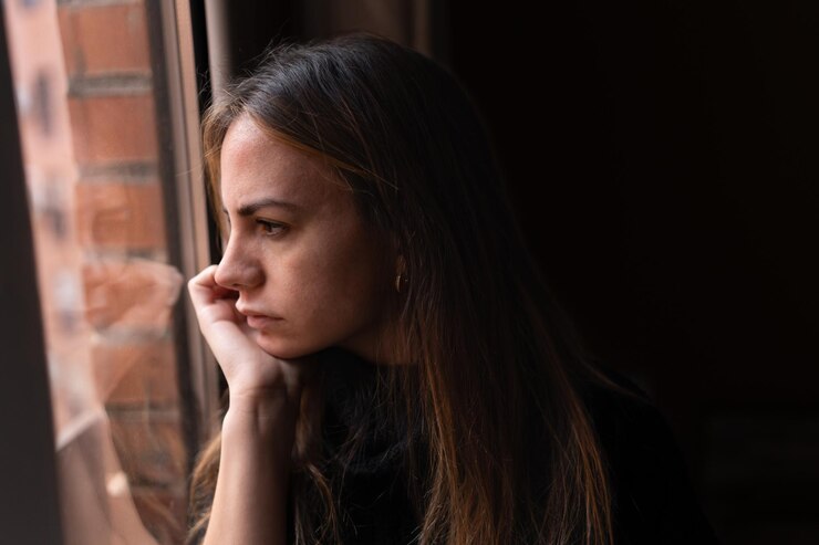 Zdjęcie zdenerwowana kobieta patrząc przez okno w domu