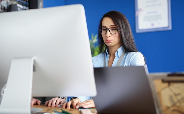 Zdenerwowana młoda kobieta pracuje przy komputerze z bliska