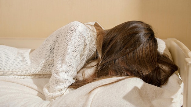 Zdjęcie zdenerwowana płacząca nastolatka z długimi włosami spadającymi na poduszkę w sypialni