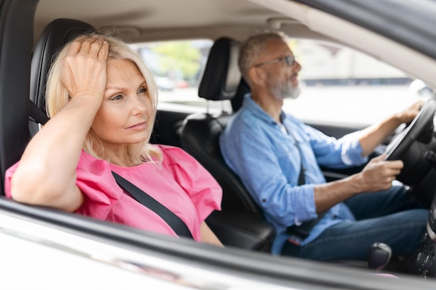 Zdenerwowana starsza kobieta siedzi obok męża prowadzącego samochód