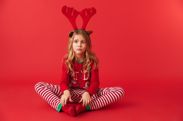 Zdenerwowany Dziewczynka Ubrana W Strój Christmas Raindeer Siedzi Na Białym Tle