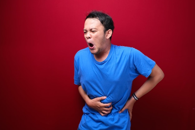 Zdenerwowany młody azjatycki mężczyzna z poważnym bólem brzucha