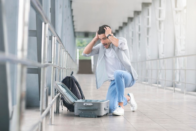 Zdesperowany i zszokowany pasażer sprawdzający swój bagaż na lotnisku