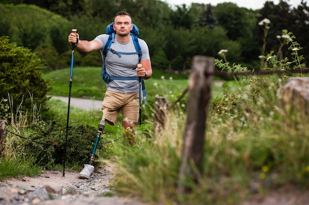 Zdeterminowany młody człowiek z protezą, próbujący uprawiać nordic walking podczas aktywnego spędzania weekendu