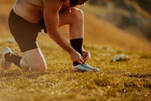 Zdeterminowany sportowiec przygotowujący się do rozpoczęcia treningu na szczycie góry o wschodzie słońca.