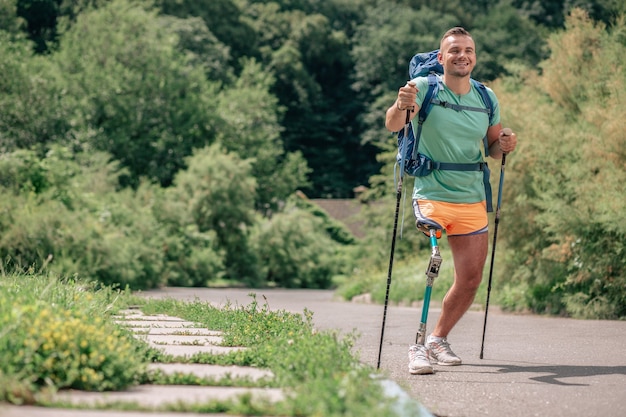 Zdeterminowany, Uśmiechnięty Młody Człowiek Z Paraliżem, Uprawiający Nordic Walking Na świeżym Powietrzu