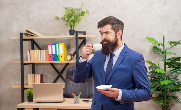 Zdezorientowany brodaty człowiek biznesu pijący kawę w biurze z profesjonalistą przestrzeni kopii