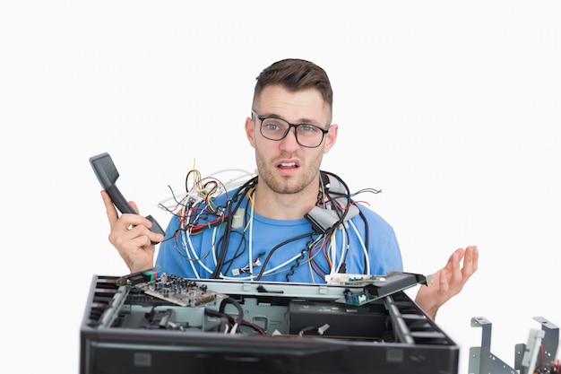 Zdjęcie zdezorientowany profesjonalista za pomocą kabli i telefonu przed otwartym procesorem