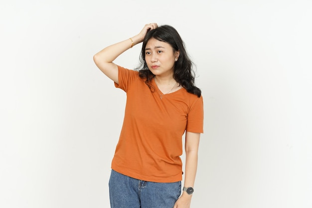 Zdezorientowany wyraz twarzy pięknej azjatyckiej kobiety noszącej pomarańczową koszulkę na białym tle