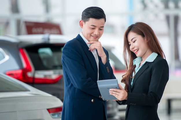 Zdjęcia azjatyckich klientów i szczęśliwych sprzedawców, którzy kupują nowe samochody, które zawierają umowy sprzedaży z dealerami samochodowymi u dealerów samochodowych.