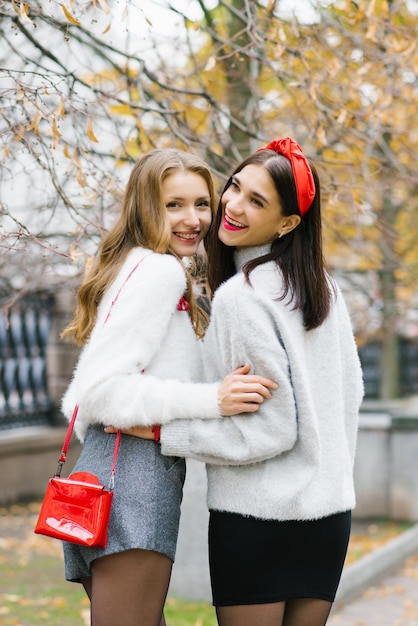 Zdjęcie zdjęcia dwóch dziewcząt uroczych przyjaciół spacerujących po jesieni w parku ciesząc się pogodą