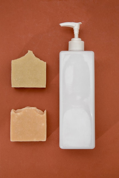 Zdjęcie białej butelki szamponu, butelki z surowicą i ręcznie robionego mydła wyizolowanego na brązowo
