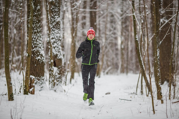 Zdjęcie biegnącego sportowca wśród drzew w zimowym lesie