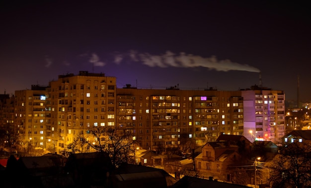 Zdjęcie budynków miejskich w nocy z fabrycznym dymem nad nimi