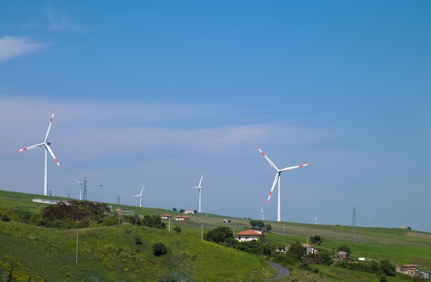 Zdjęcie dużych turbin wiatrowych stojących na polu na tle nieba i chmur