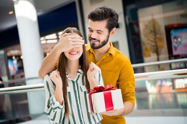 Zdjęcie dwóch osób atrakcyjna dama przystojny facet para nieoczekiwane zamknięcie oczu przygotowane niespodzianka pudełko rocznica data wizyta sklep centrum handlowe nosić casual dżinsy koszula strój w pomieszczeniu
