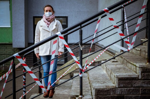 Zdjęcie dziewczyny w masce stojącej na ulicy z taśmami ostrzegającymi o niebezpieczeństwie