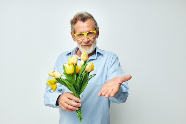Zdjęcie emerytowanego staruszka żółty bukiet kwiatów pozowanie na jasnym tle