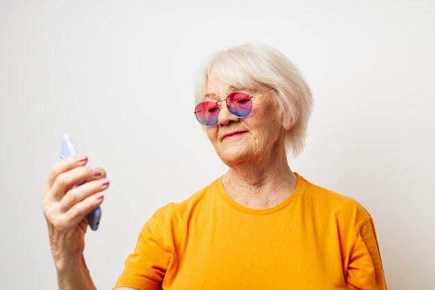 Zdjęcie emerytowanej staruszki w żółtej koszulce pozującej komunikacja przez telefon emocje zbliżenia