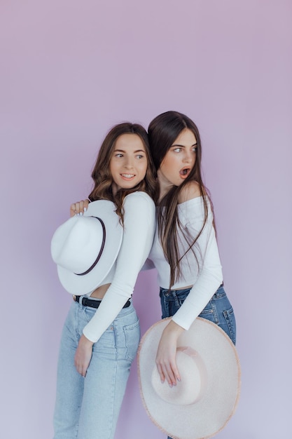 Zdjęcie emocjonalnych przyjaciół dwóch kobiet stojących na białym tle na fioletowym tle.