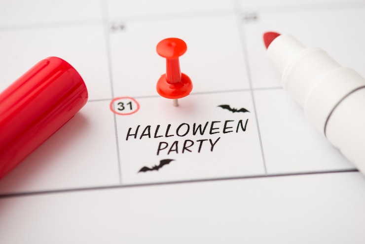 Zdjęcie zdjęcie etykiety z datą 31 października z napisem halloween party dwa nietoperze czerwony pin i znacznik na białym tle na tle kalendarza