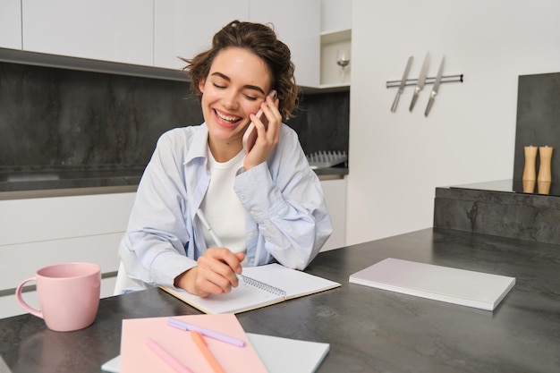 Zdjęcie zdjęcie kobiety pracującej w domu i spisującej informacje podczas rozmowy telefonicznej, dzwoniącej do kogoś, kto używa
