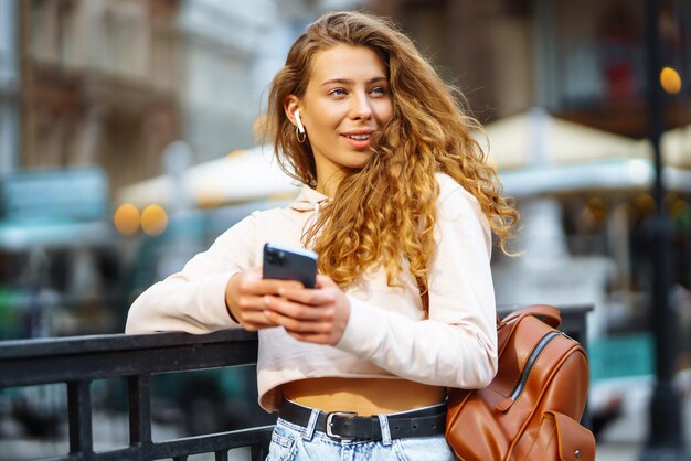 Zdjęcie kobiety używającej smartfona Kobieta wysyłająca wiadomości na ulicy Piękna kobieta spędzająca czas w mieście