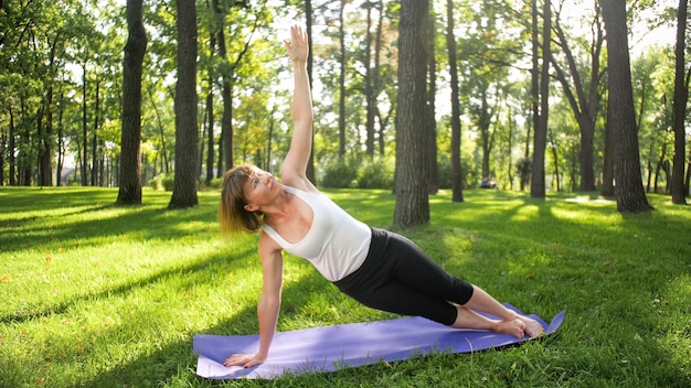 Zdjęcie kobiety w średnim wieku uprawiania jogi lub fitness na świeżej zielonej trawie w parku. Zdrowie fizyczne i psychiczne kobiet. Osoba w medytacji i harmonii ciała i duszy