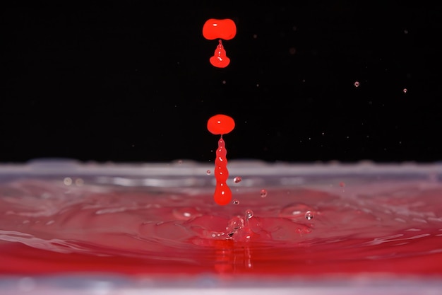 Zdjęcie ładnej czerwonej kropli wody na czarnym tle